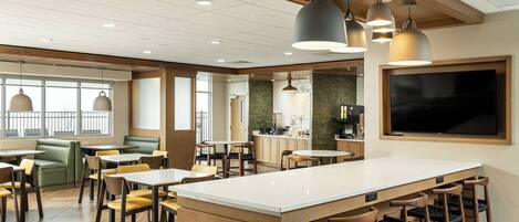 A modern restaurant with a central island, booths, and a bar area.