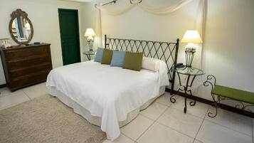 Quarto com cama, luminárias de cabeceira, cômoda, espelho e porta verde.