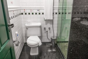 Un baño pequeño con inodoro, bidé y cabina de ducha de vidrio.