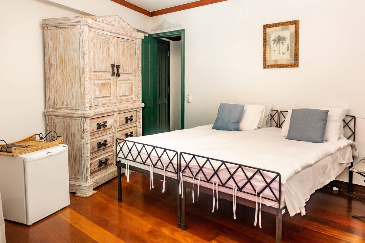 Un dormitorio con una cama, un armario y un refrigerador pequeño.