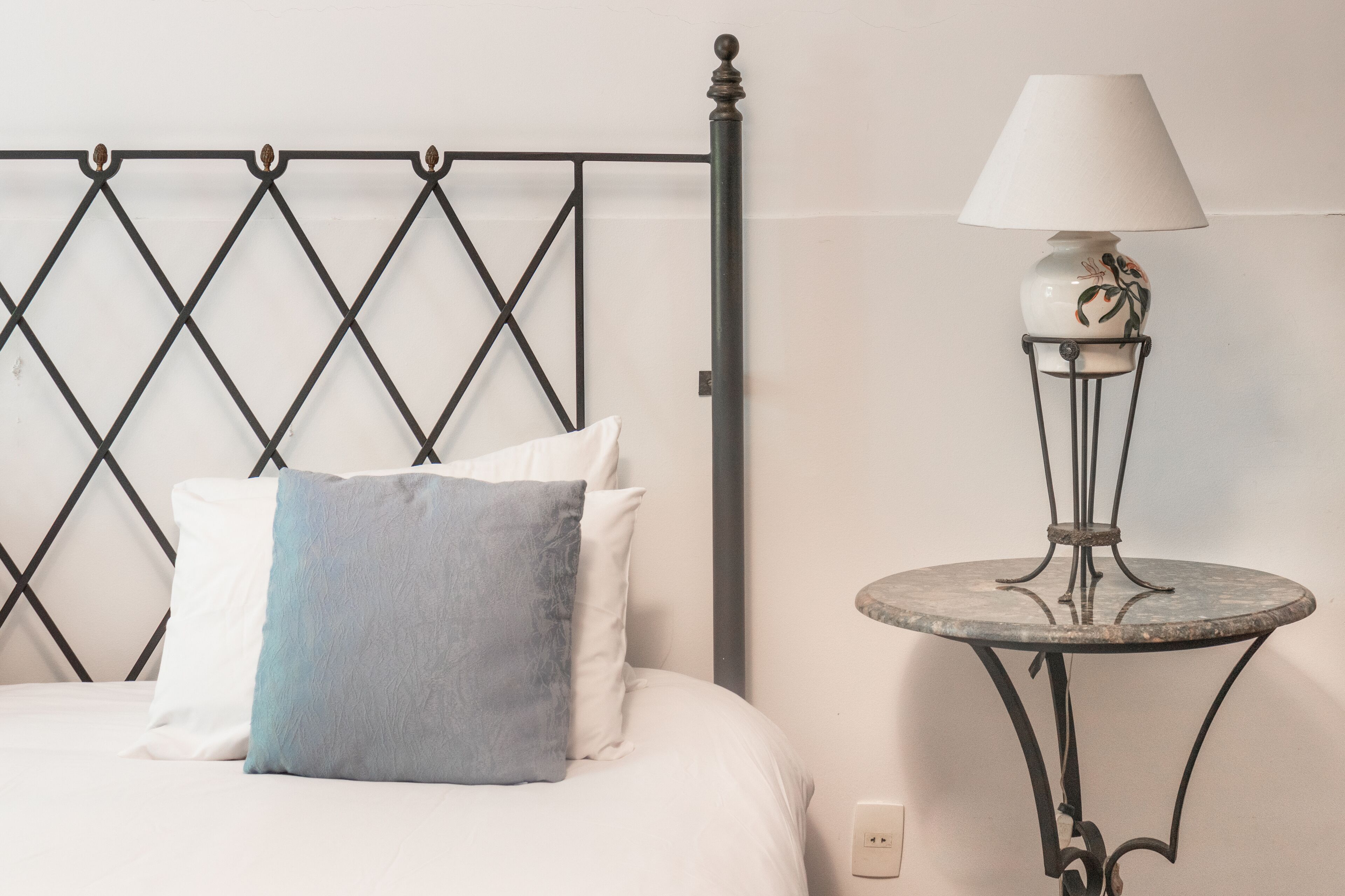 A bed with a headboard, pillows, and a bedside table with a lamp.