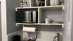 Un angolo cottura compatto con forno a microonde, macchina del caffè e lavello.