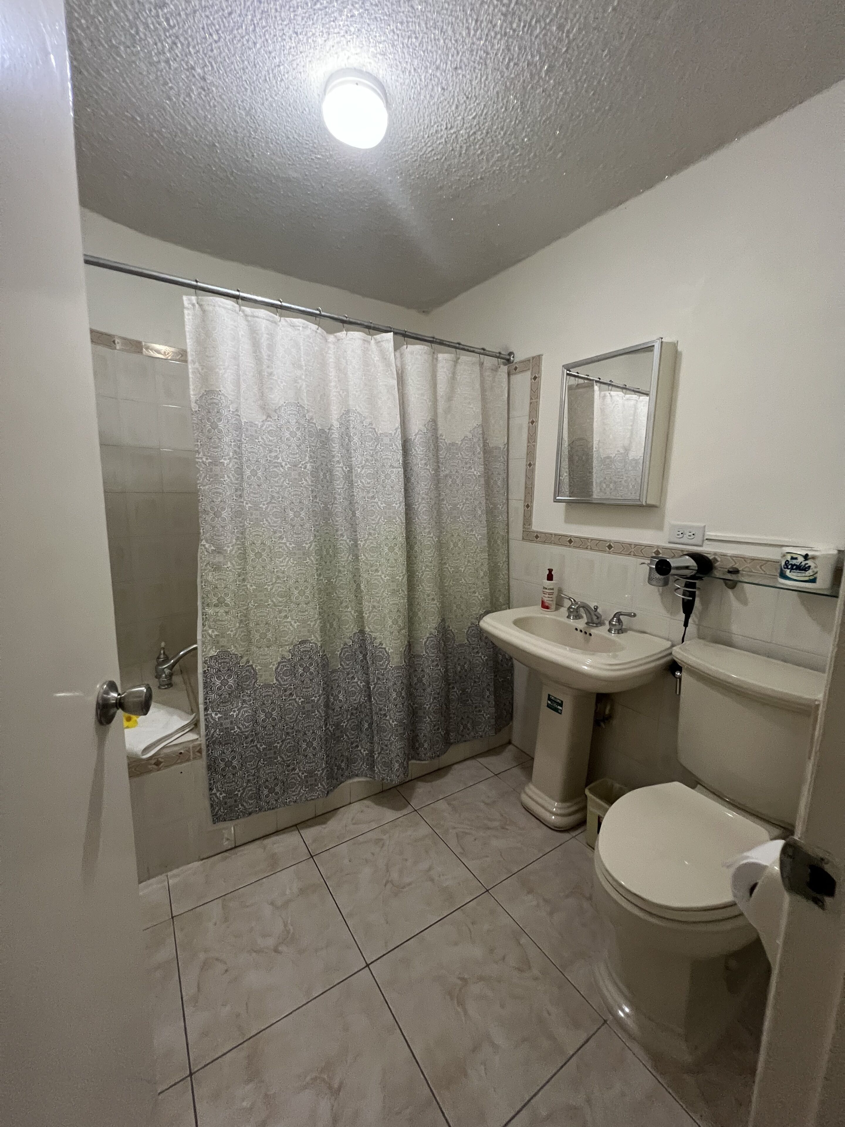 A bathroom with a shower, sink, and toilet.