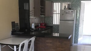 A compact kitchen with a dining area, a refrigerator, and a tiled floor. - Casa com Lazer Completo (Cidade Ocidental)