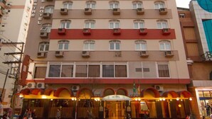 A multi-story hotel with balconies, a ground-level restaurant, and a visible flag.