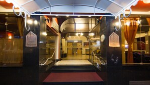 A hotel entrance with a glass facade, a red carpet, and a sign indicating it is the San Silvestro Palace Hotel.