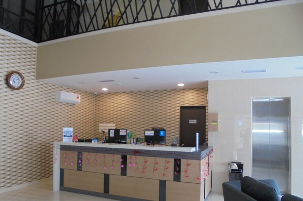 A reception desk with multiple monitors, a clock, and a sign indicating a 24-hour service. - Kampar Boutique Hotel (Kampar)