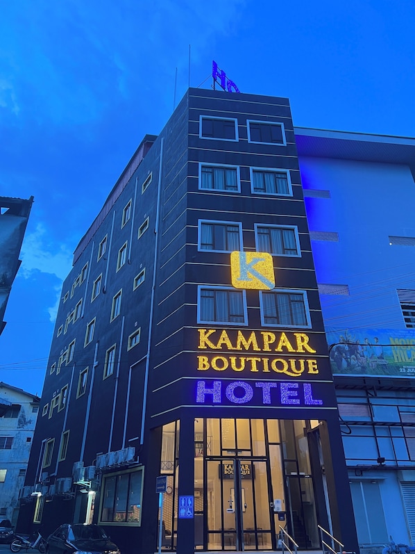 Un hotel con un cartel llamativo que dice 'KAMPAR BOUTIQUE HOTEL' y una entrada visible.