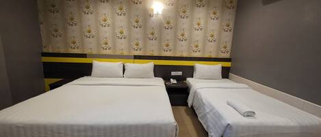 A hotel room with two beds, a nightstand with a phone, and a wall-mounted light.