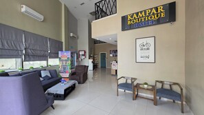 Un vestíbulo de hotel con mostrador de recepción, zona de estar y un cartel que dice 'Kampar Boutique Hotel'.