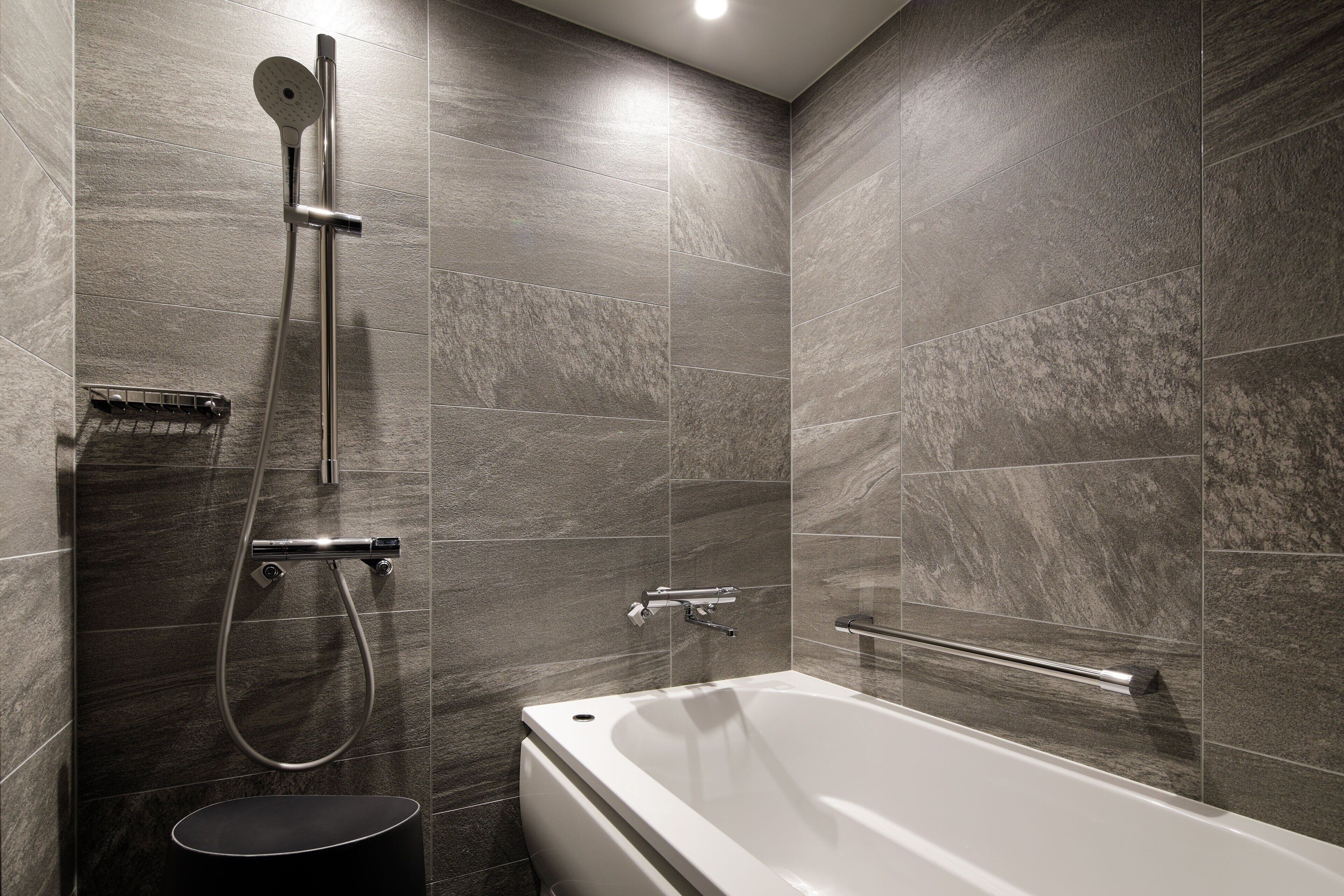Un baño moderno con una bañera, una ducha con manguera y un perchero para toallas.