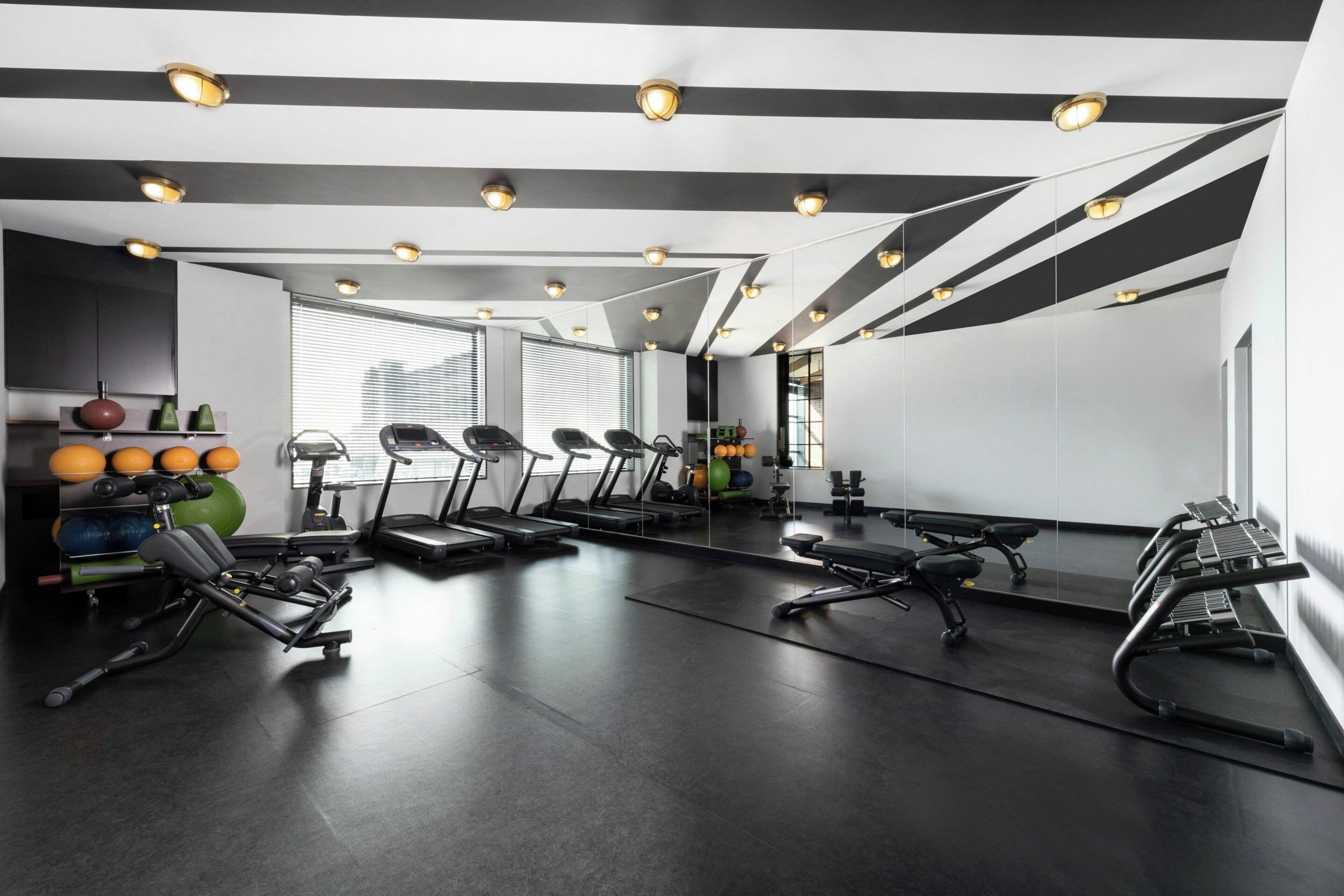Un gimnasio moderno con equipo de ejercicio, una cinta de correr y un espejo grande.
