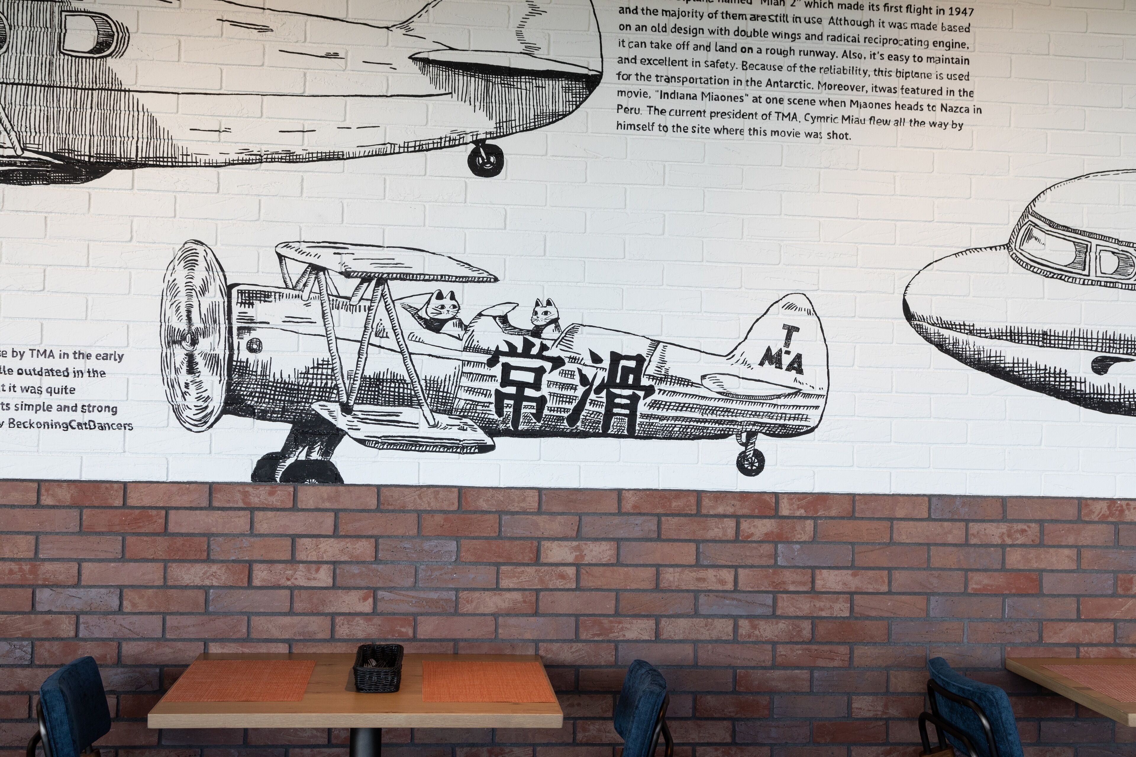 A mural of vintage aircraft on a brick wall in a restaurant setting.