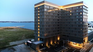 Een meerlaags hotel met een modern design, inclusief een parkeerplaats en uitzicht op het water.