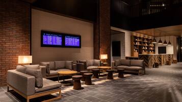 A modern lounge area with sofas, round tables, and a digital display wall.