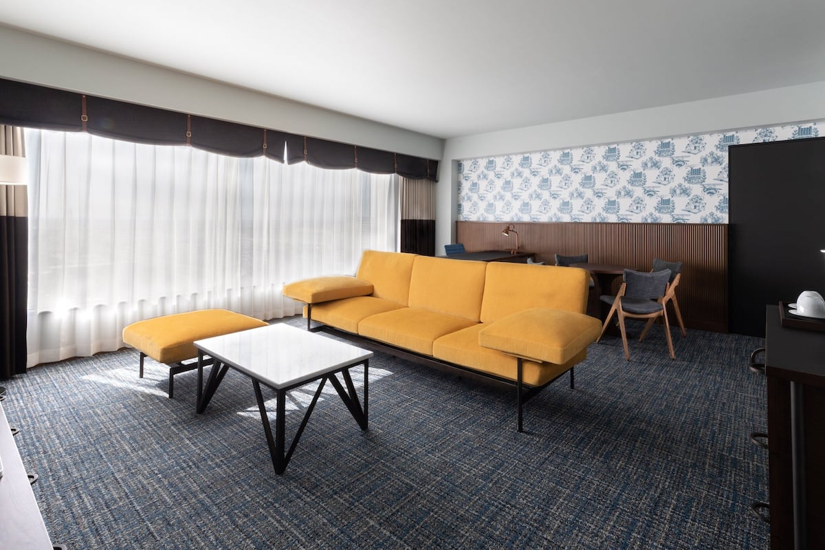 Une chambre d’hôtel équipée d’un canapé, d’une petite table, d’une chaise, d’un bureau et d’une télévision.