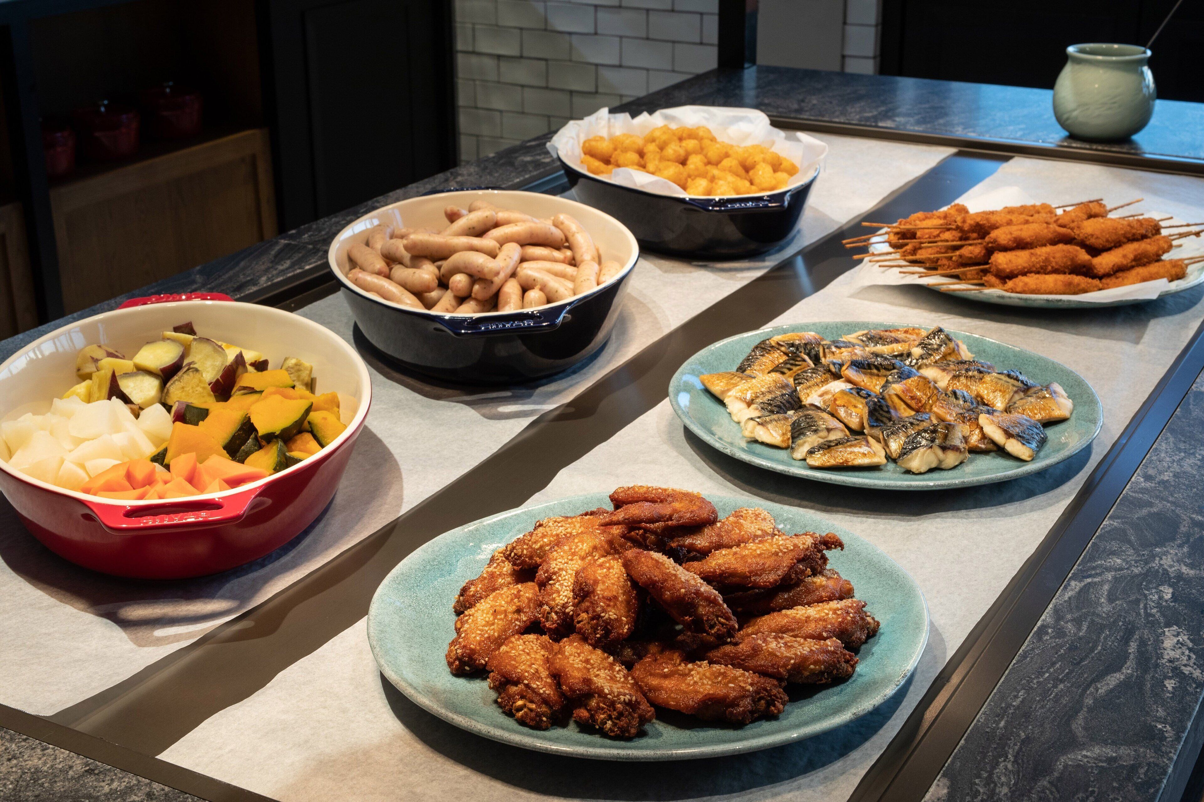 Ein Buffet mit verschiedenen Speisen, darunter gebratenes Hähnchen, Gemüse und andere Snacks.