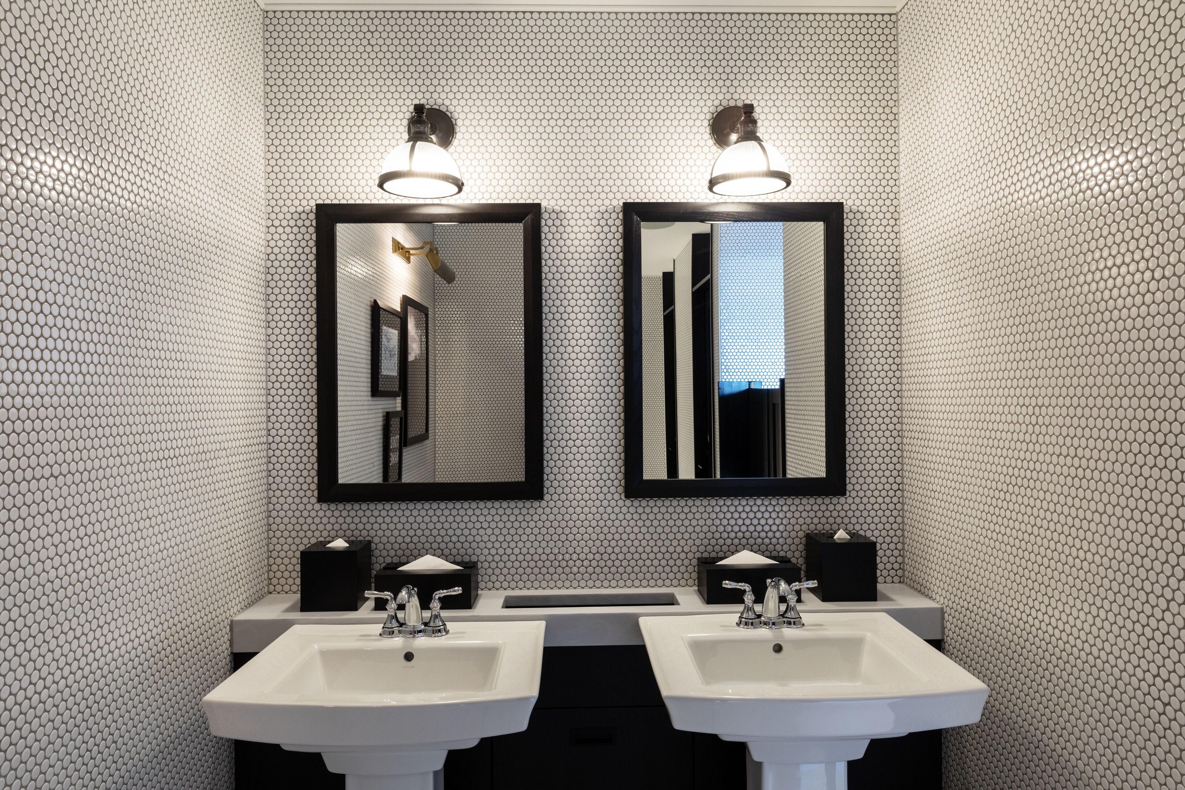 A bathroom with two sinks, two mirrors, and two wall-mounted light fixtures.