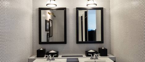 A bathroom with two sinks, two mirrors, and two wall-mounted light fixtures.