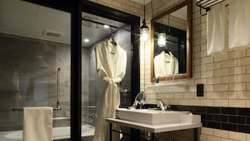 Un baño moderno con ducha envuelta en vidrio, un lavabo blanco y un espejo grande.