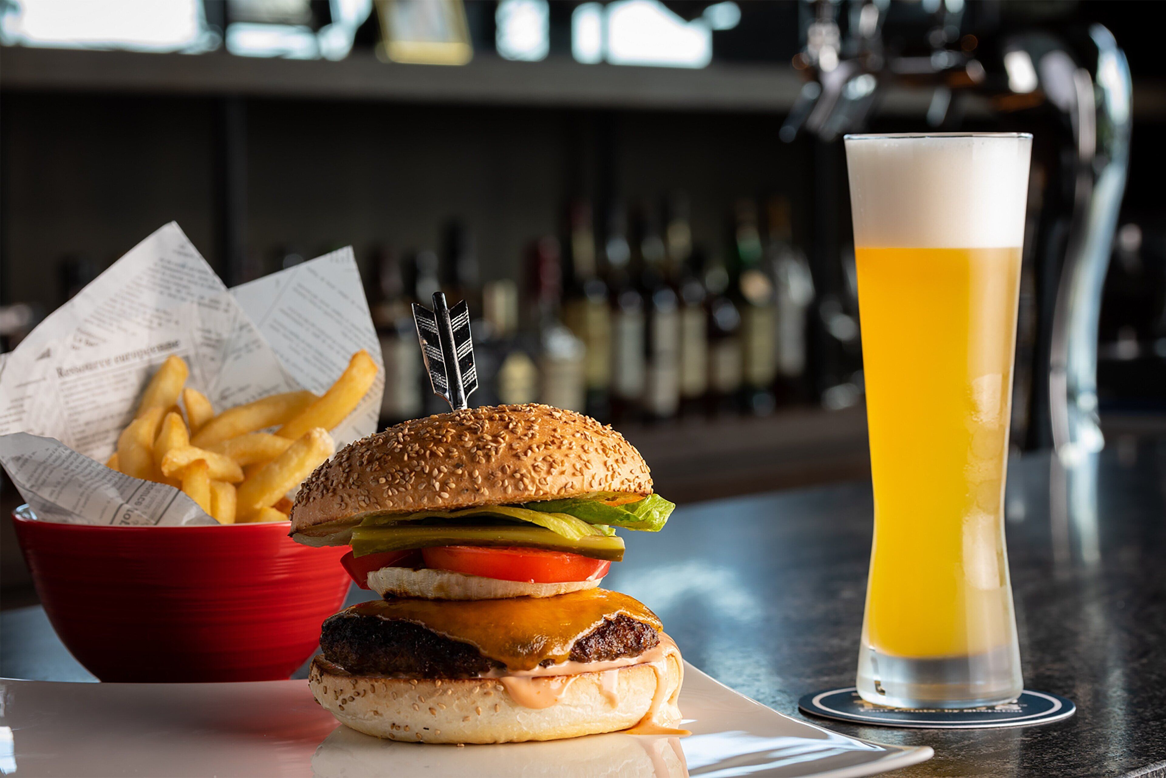 A burger with fries and a glass of beer on a table.