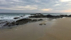 A beach with a rocky shoreline and a wide sandy area. - Casa del Mar (Santa María Tonameca)
