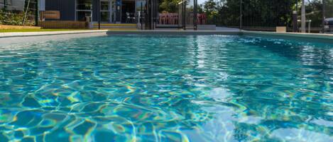 Una piscina cristalina con vista a un edificio al fondo.