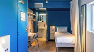 Habitación de hotel con cama, escritorio y baño visible a través de una puerta abierta.