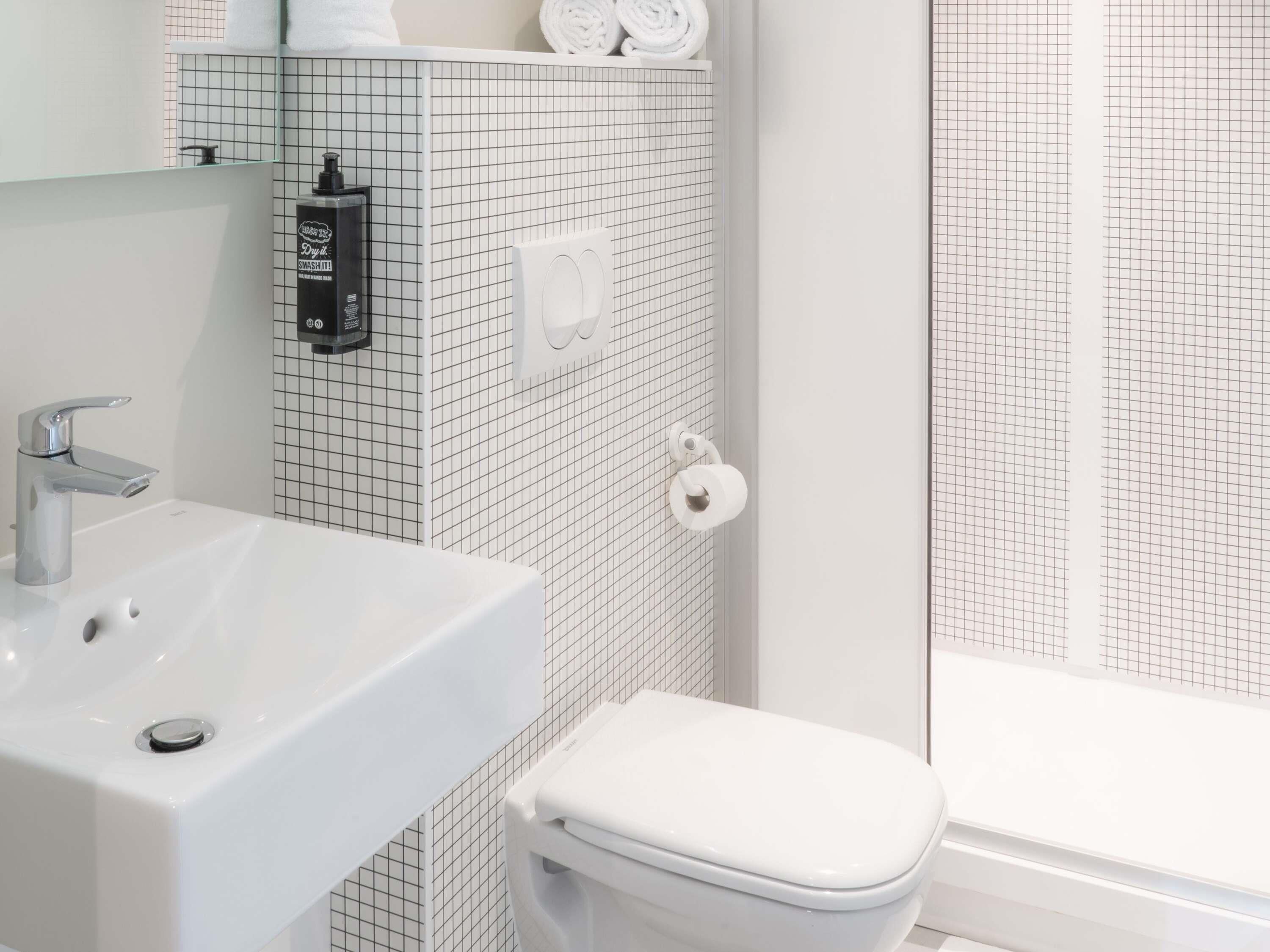 Un baño con lavamanos blanco, inodoro y zona de ducha.
