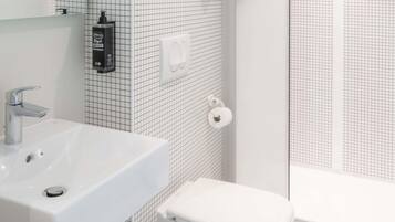 Un baño con lavamanos blanco, inodoro y zona de ducha.