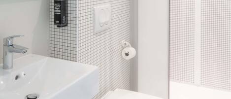 Un baño con lavamanos blanco, inodoro y zona de ducha.