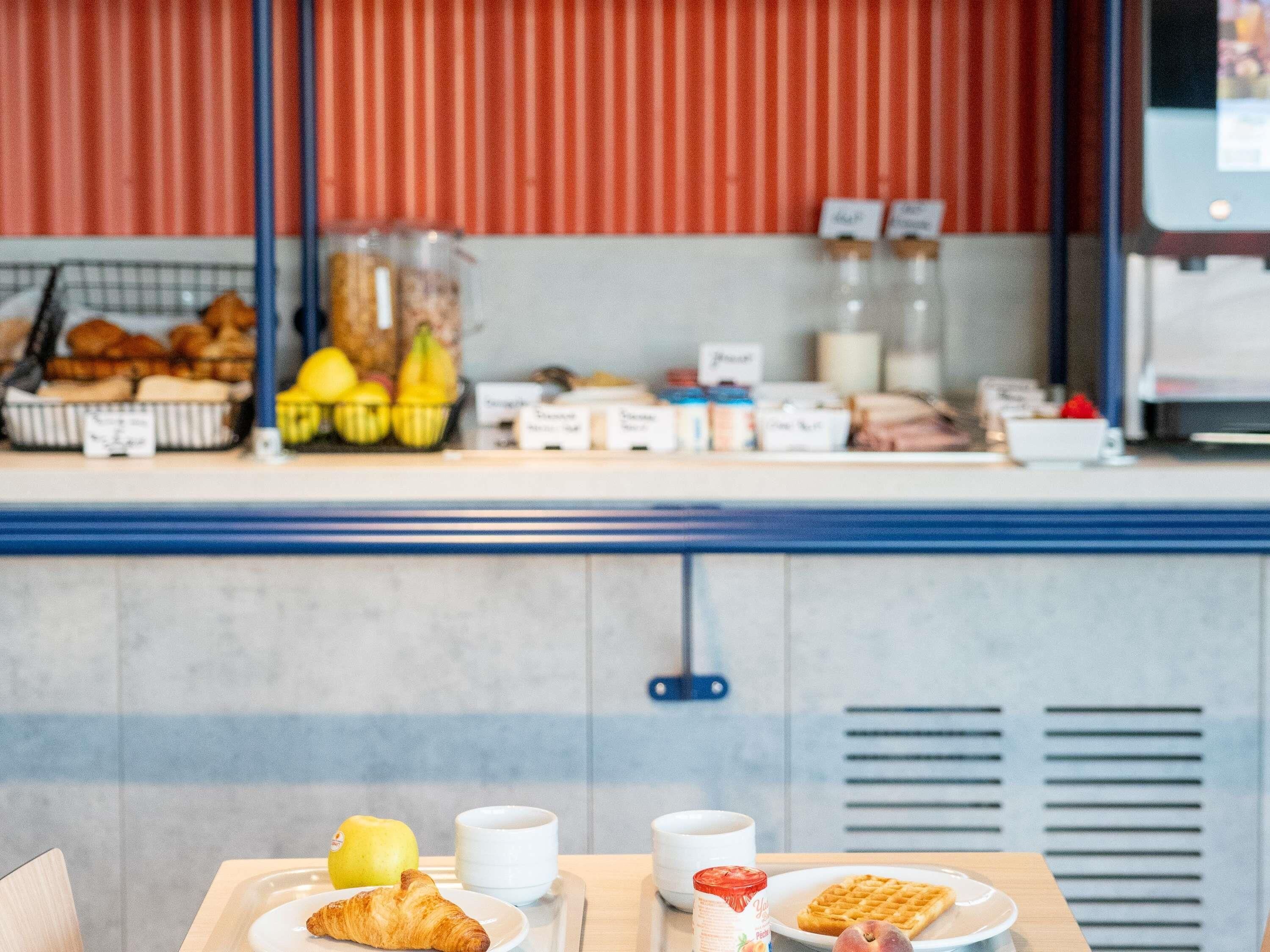 A breakfast buffet with pastries, fruits, and beverages.