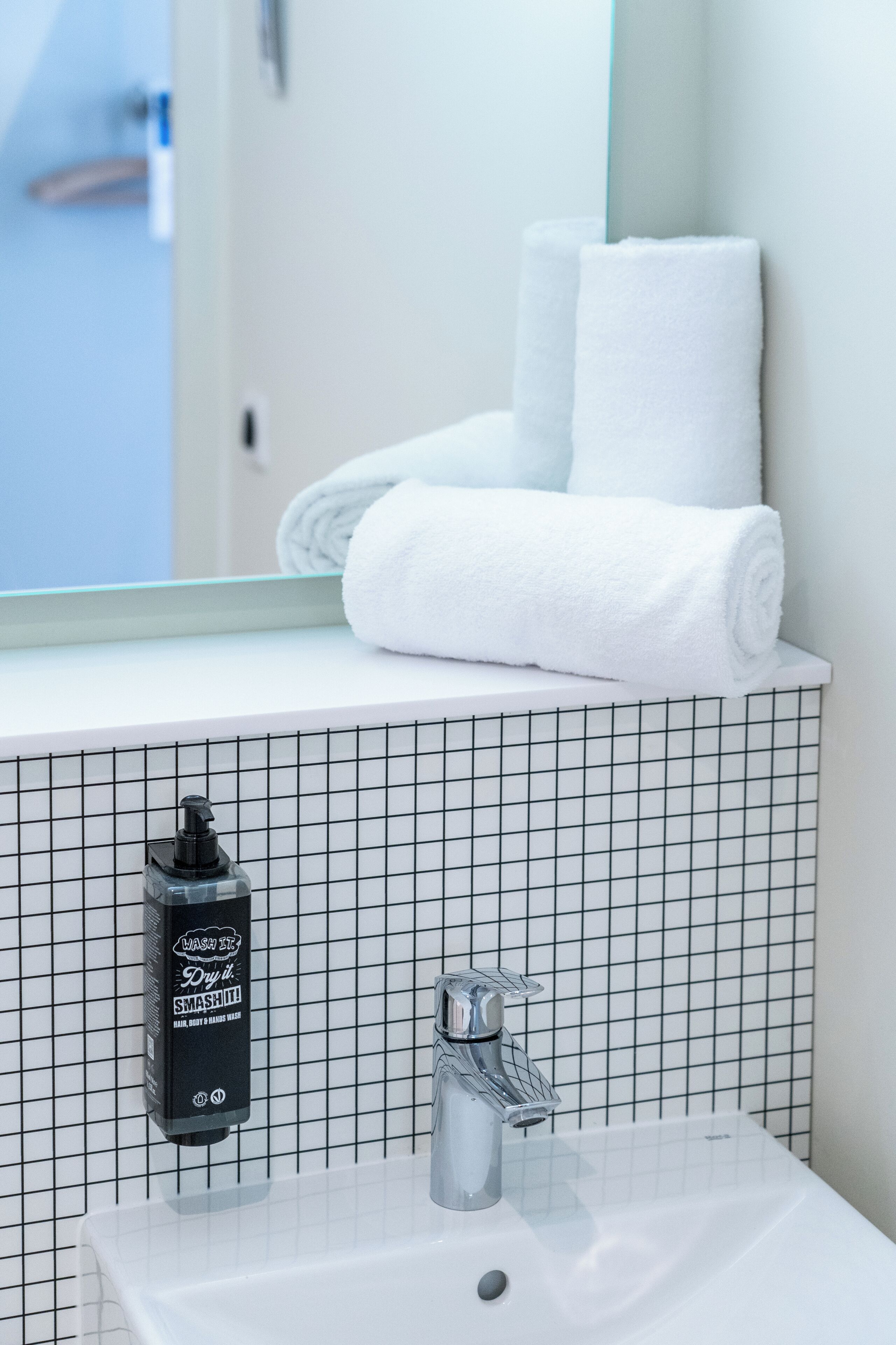 A bathroom with a white sink, a mirror, and a towel rack.