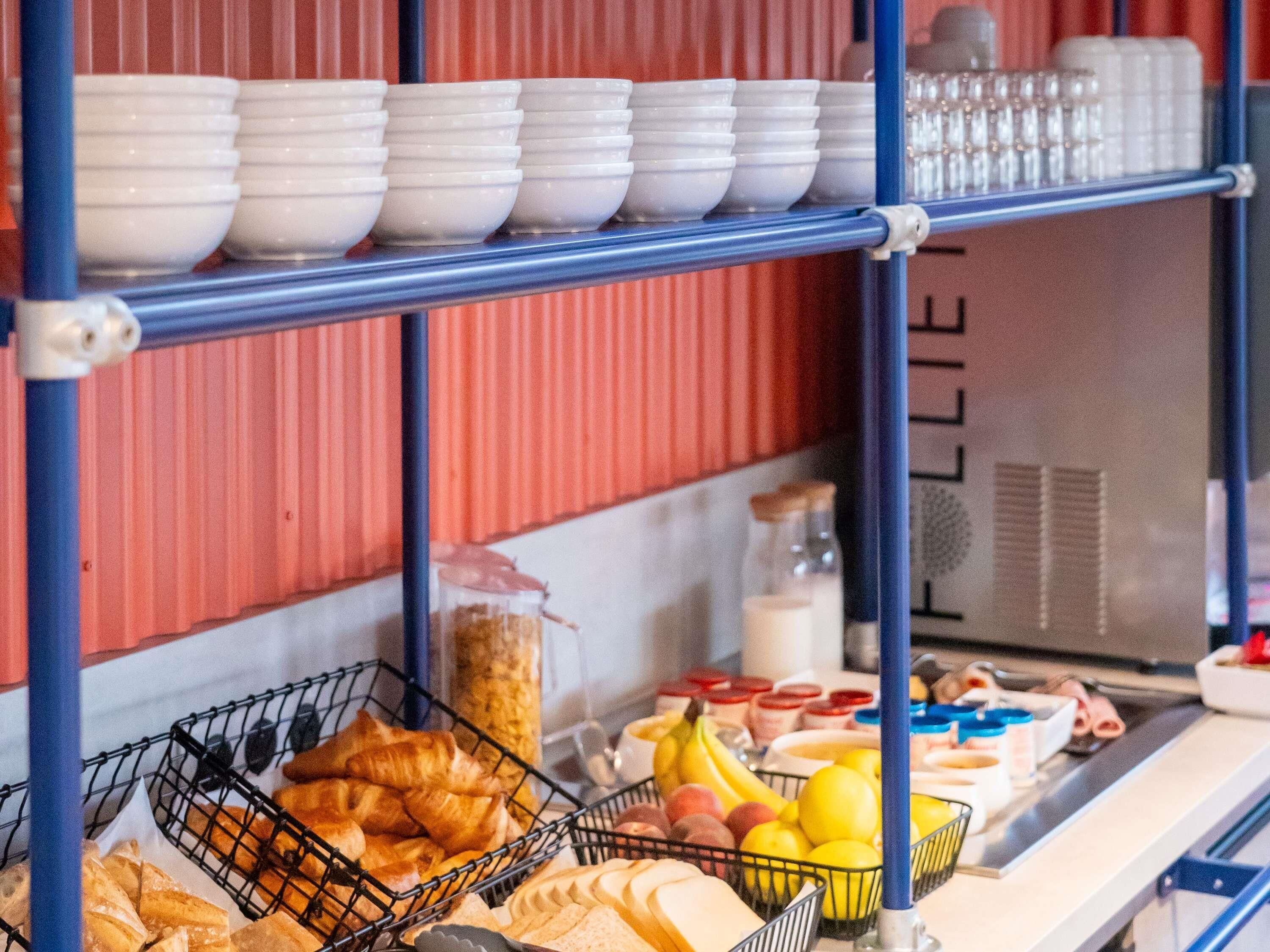 Een ontbijtbuffet met brood, gebak, fruit en zuivelproducten.