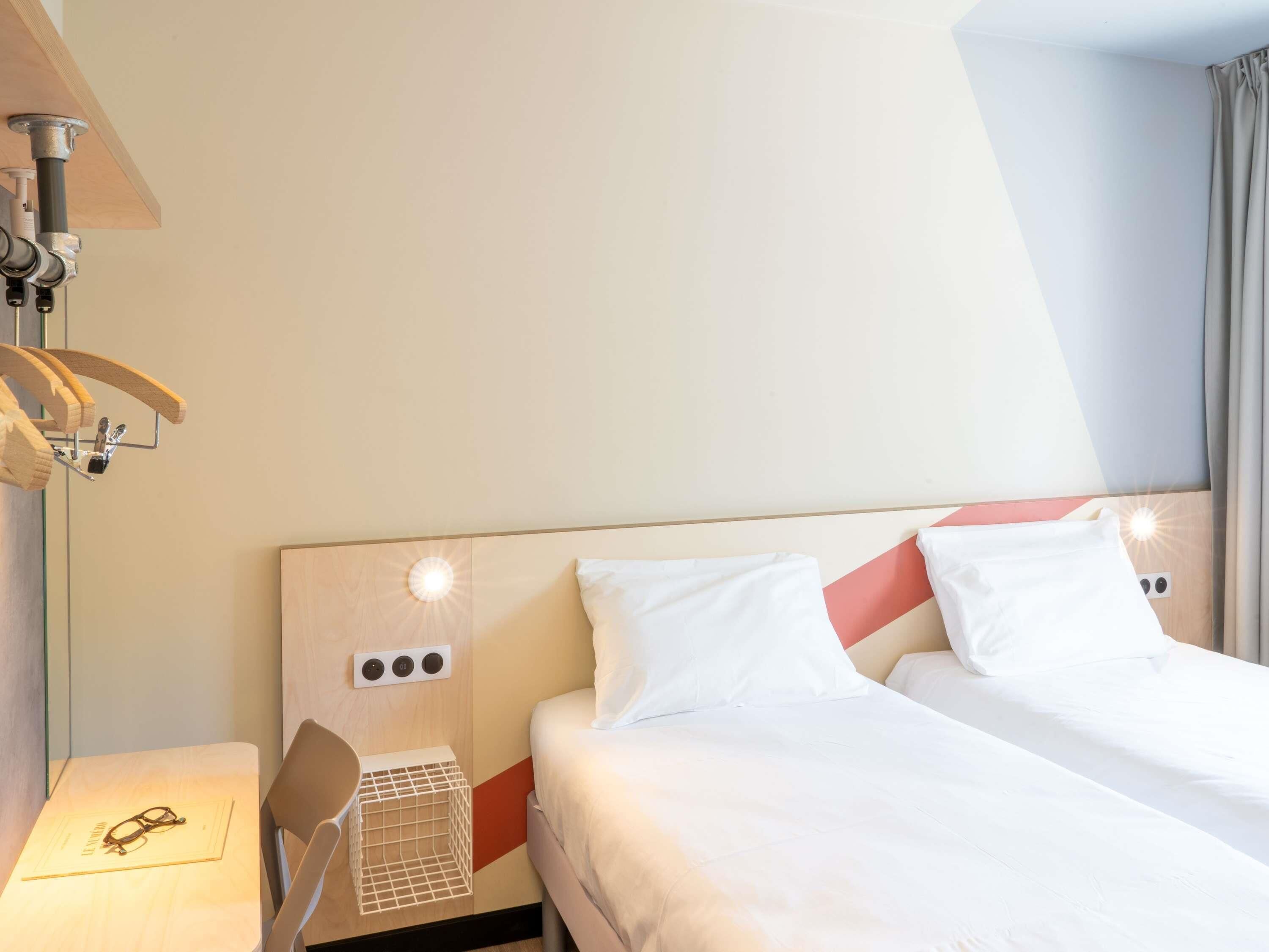 Ein Hotelzimmer mit einem Bett, einem Sessel, einem Tisch mit Gläsern und einer Wandlampe.