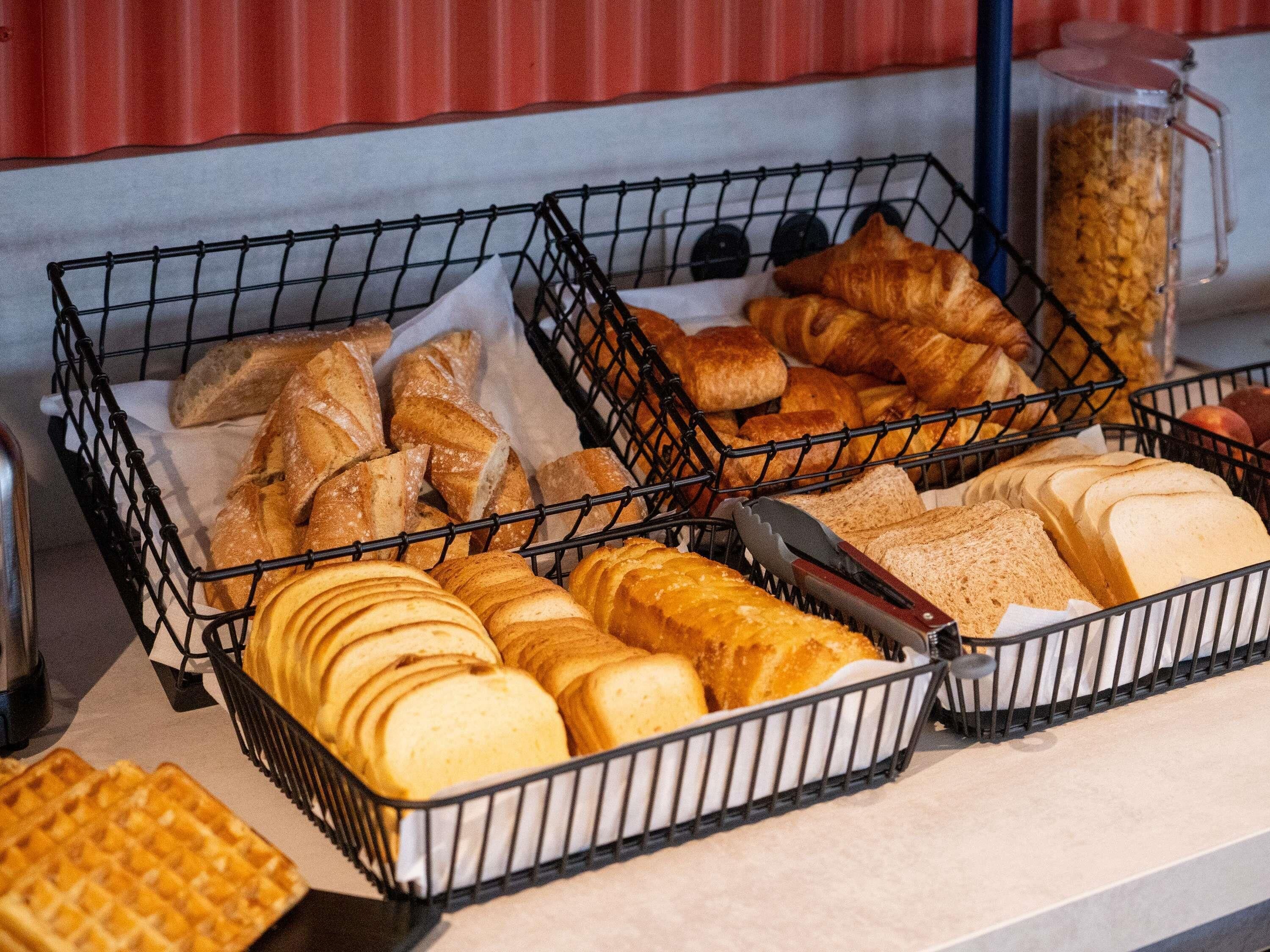 A display of various breads and pastries in wire baskets.