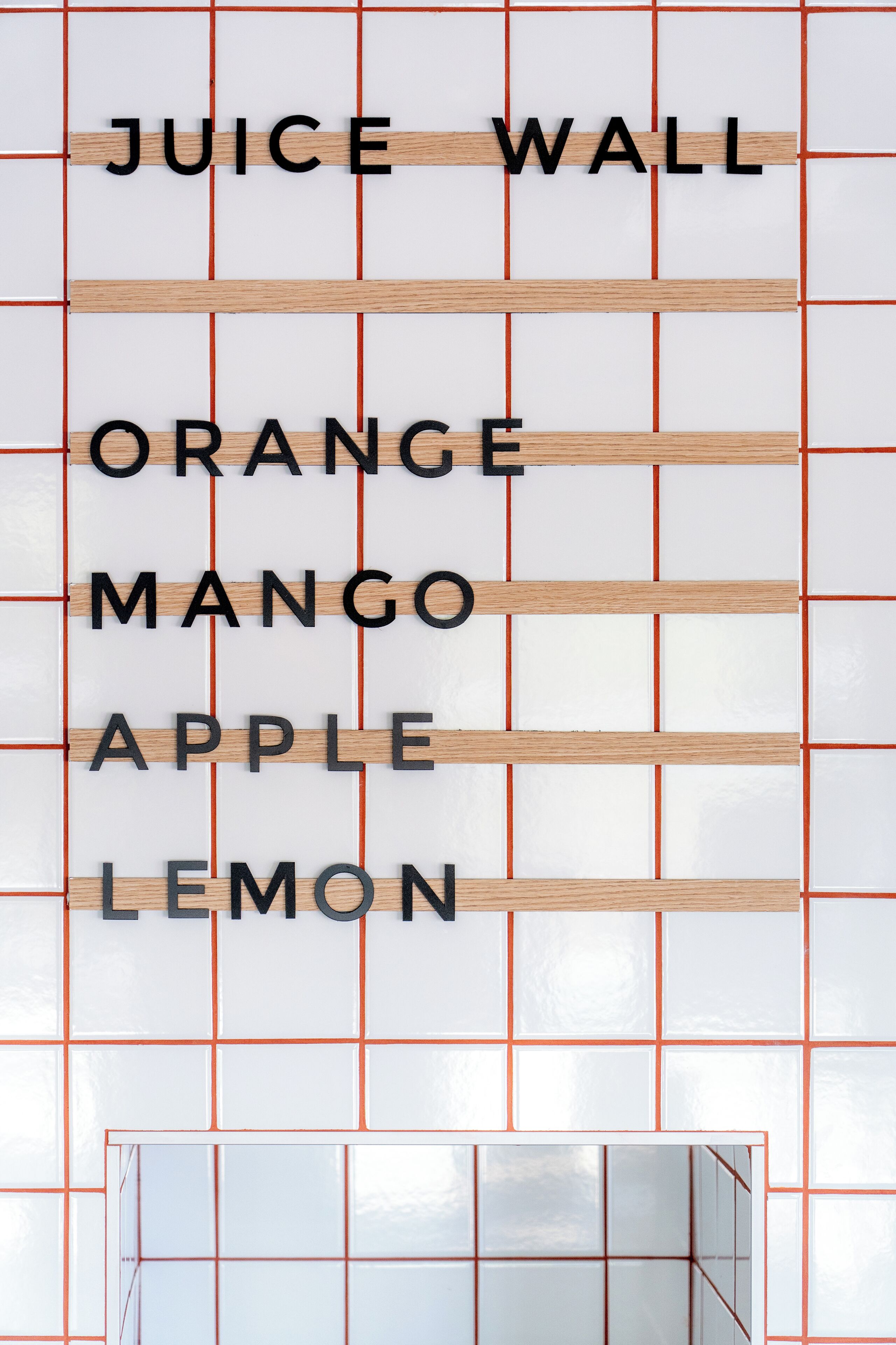 A wall with the text 'JUICE WALL ORANGE MANGO APPLE LEMON' indicating a juice bar.