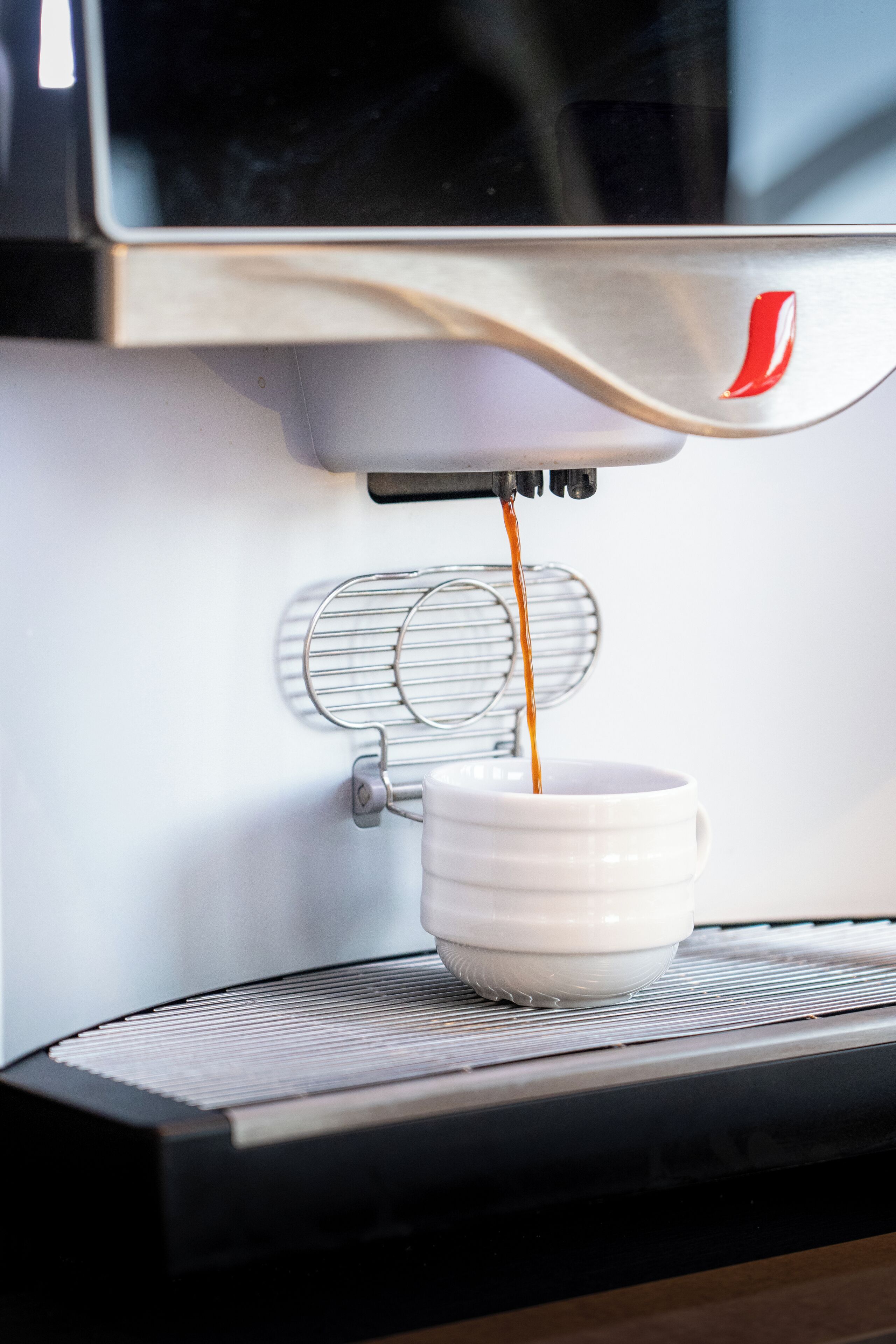 Eine Kaffeemaschine füllt Kaffee in eine weiße Tasse.