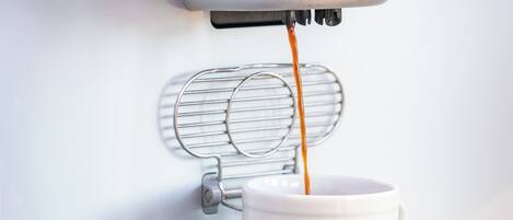 Eine Kaffeemaschine füllt Kaffee in eine weiße Tasse.
