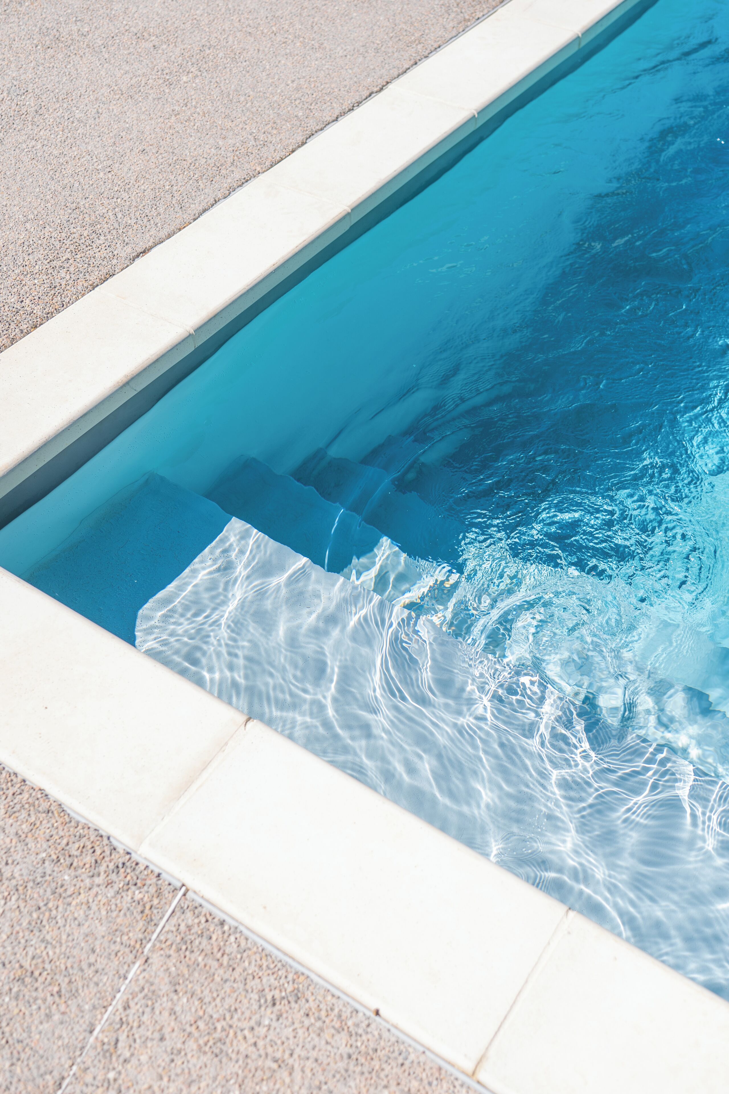 Una piscina con agua azul cristalina y borde de azulejos.