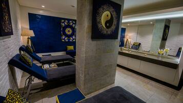 A modern spa room with massage tables, a blue patterned wall, and a yin-yang symbol on the wall.