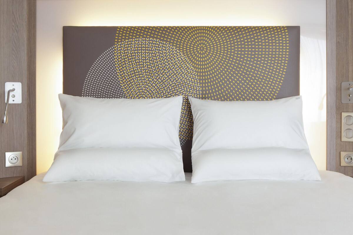 A bed with white pillows and a headboard with a geometric pattern.