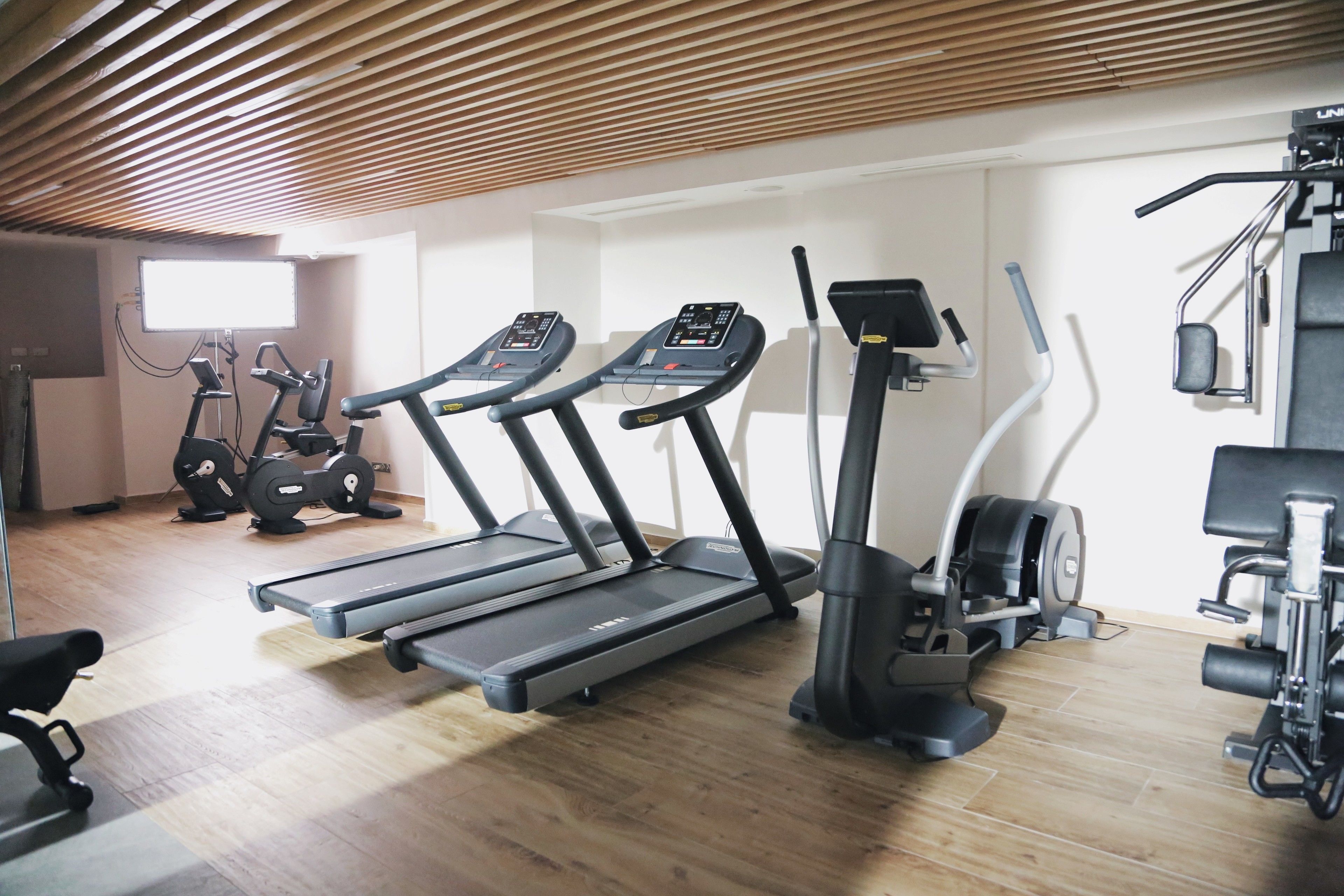 Une salle de sport équipée de tapis de course, de vélos elliptiques et d’un vélo d’appartement.