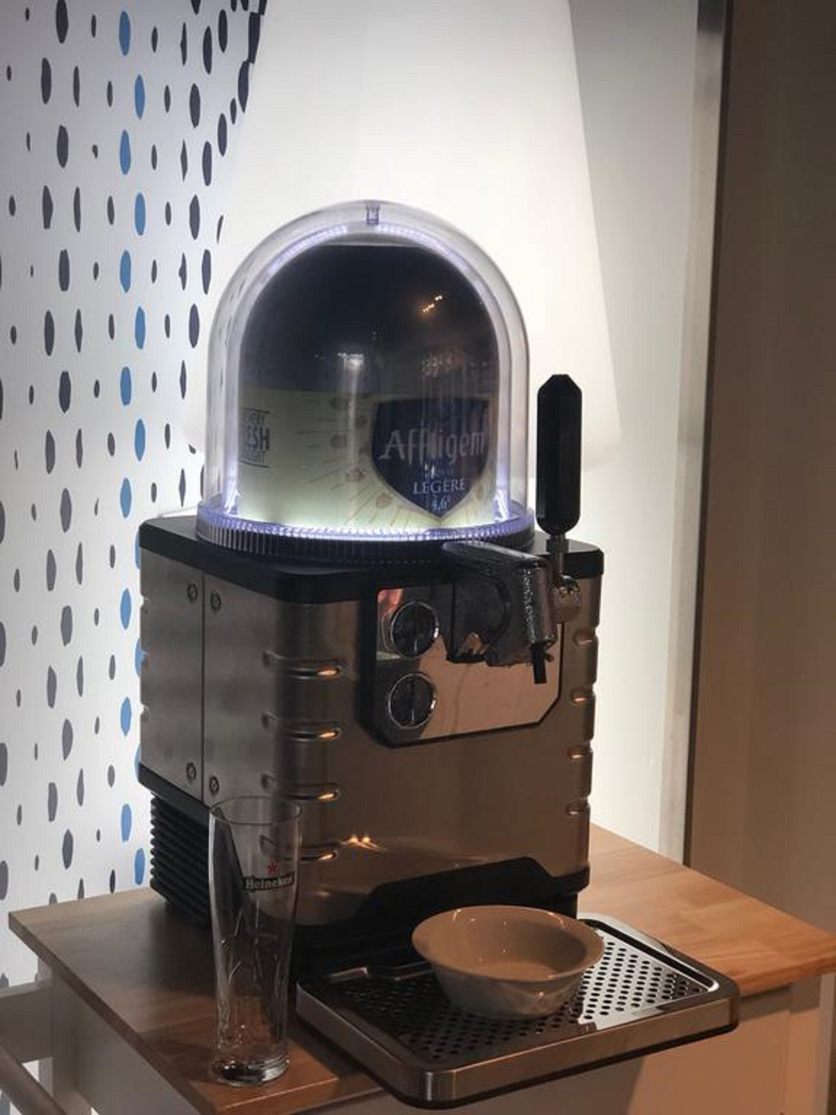 A coffee machine with a transparent dome and a glass container on a wooden table.