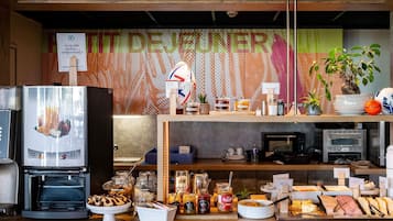 A café counter with a coffee machine, jars of condiments, and a variety of food items.