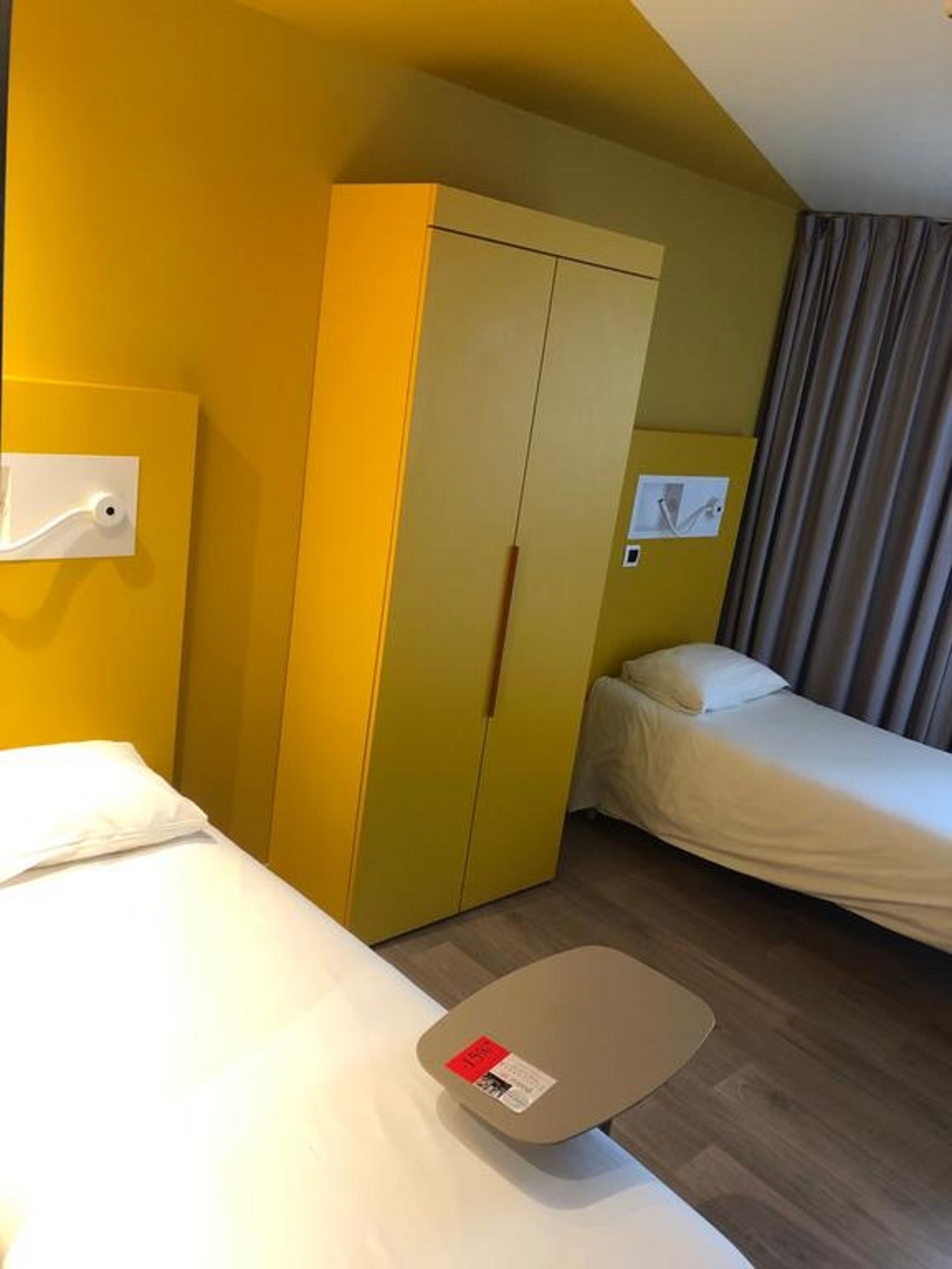 Ein Hotelzimmer mit zwei Betten, einem Kleiderschrank und einem kleinen Tisch.