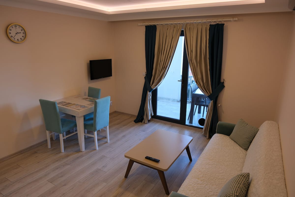 A living room with a sofa, a small table, and a dining table with chairs.