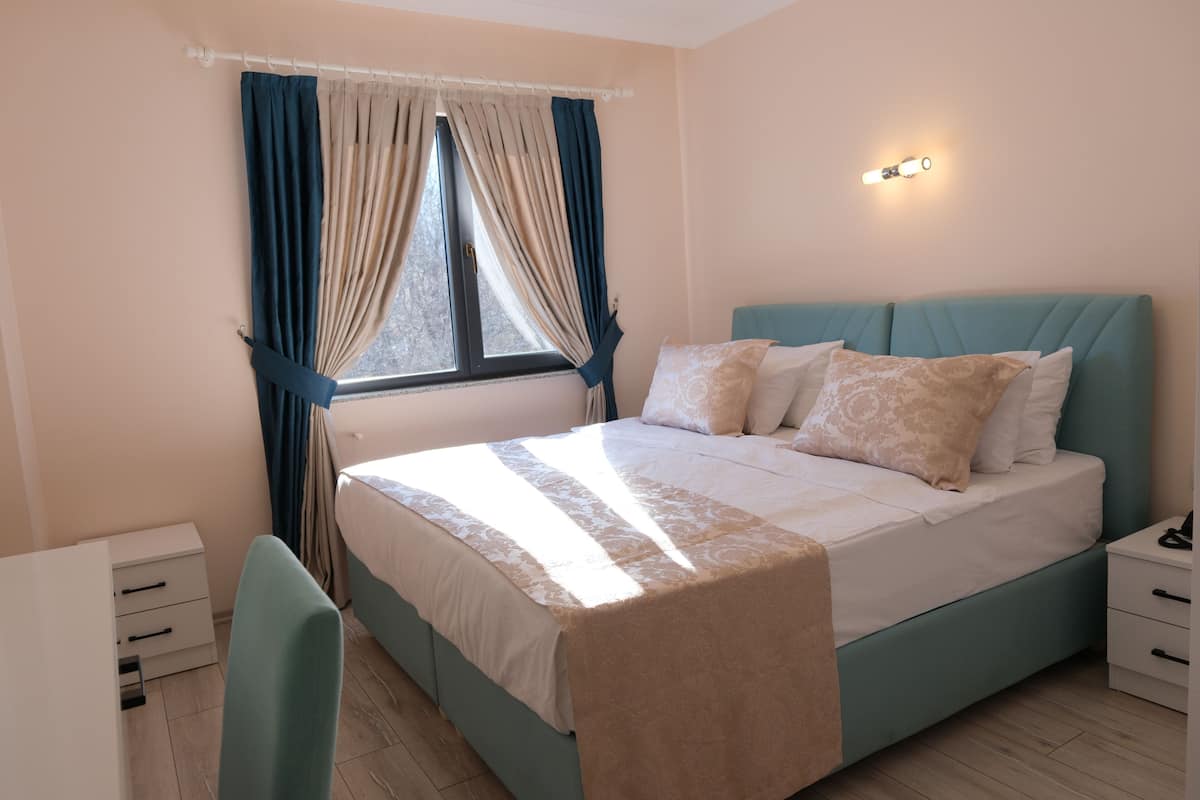 A bedroom with a bed, bedside tables, a desk, and a chair.