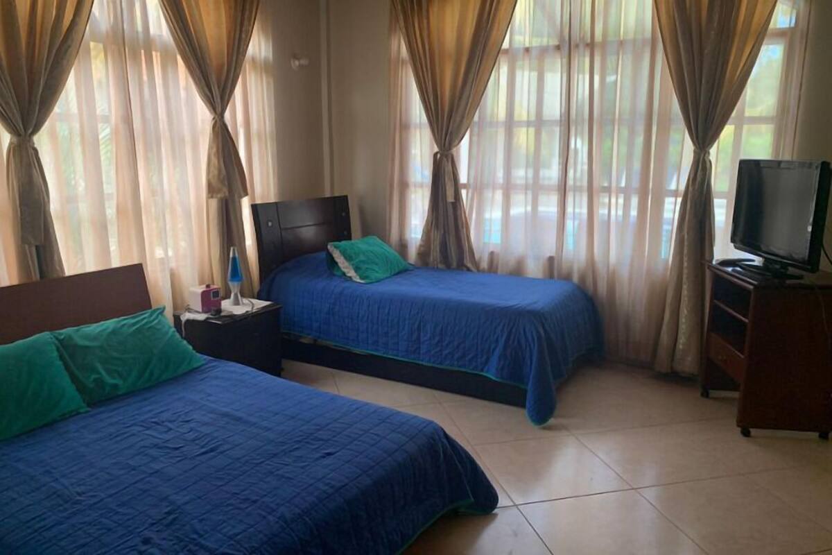 A hotel room with two beds, a TV, and curtains.