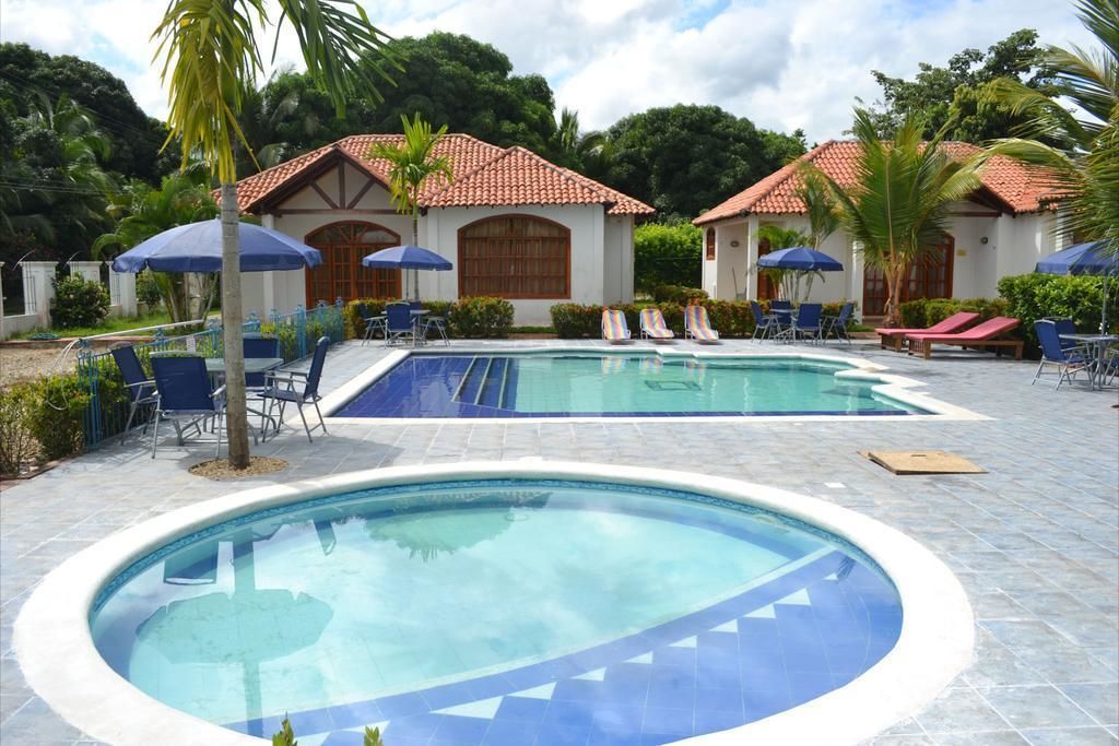 A pool area with two pools, lounge chairs, and umbrellas.